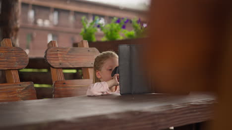 Little-girl-plays-game-online-by-tablet-in-cafe-on-rainy-day