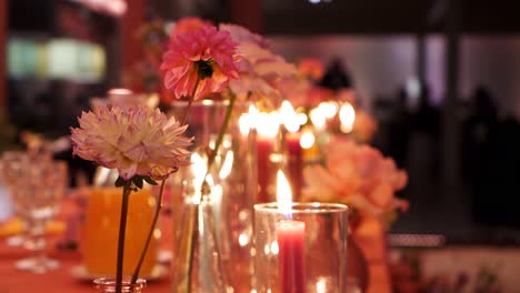 Flores-Rosadas-Con-El-Telón-De-Fondo-De-Velas-Encendidas-En-Recipientes-De-Vidrio