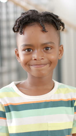 vertical video: smiling african american child wearing striped shirt, looking at camera indoors