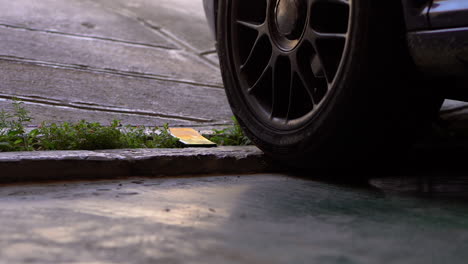 Close-up-slow-motion-shot-of-car-tires-going-over,-bending-smartphone-on-a-ditch---smartphone-doesn't-break