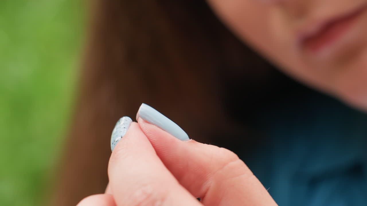 Close up of stylist threading needle with gentle care, blue polished nails and soft focus revealing precision, patience, and artistry, capturing delicate craftsmanship and creative concentration