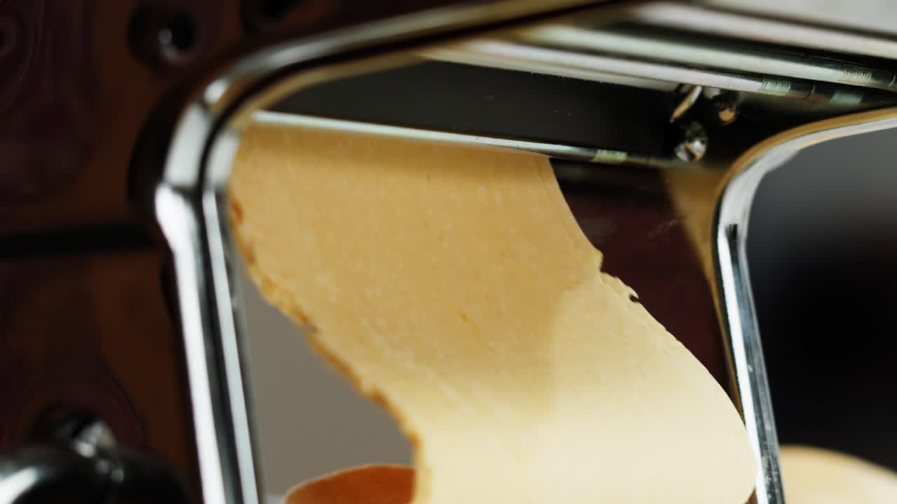 Fresh Pasta Dough Being Rolled Through a Manual Pasta Maker