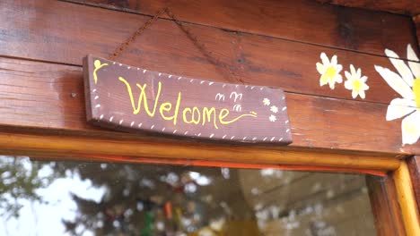 welcome wooden sign hanging on a rustic door