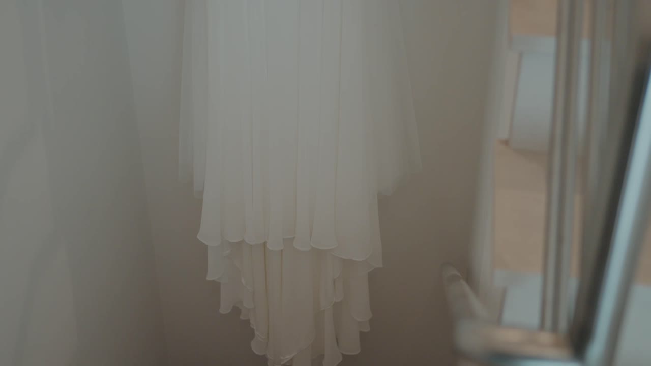 белые свадебные платья висят в помещении, создавая мягкую и спокойную атмосферу перед церемонией.