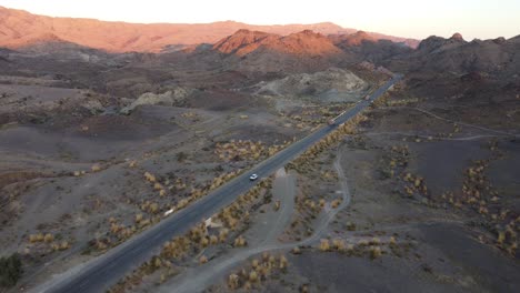 Aerial-view-of-a-car-driving-on-national-highway-in-the-Balochistan-province-of-Pakistan-at-sunset,-Kalat