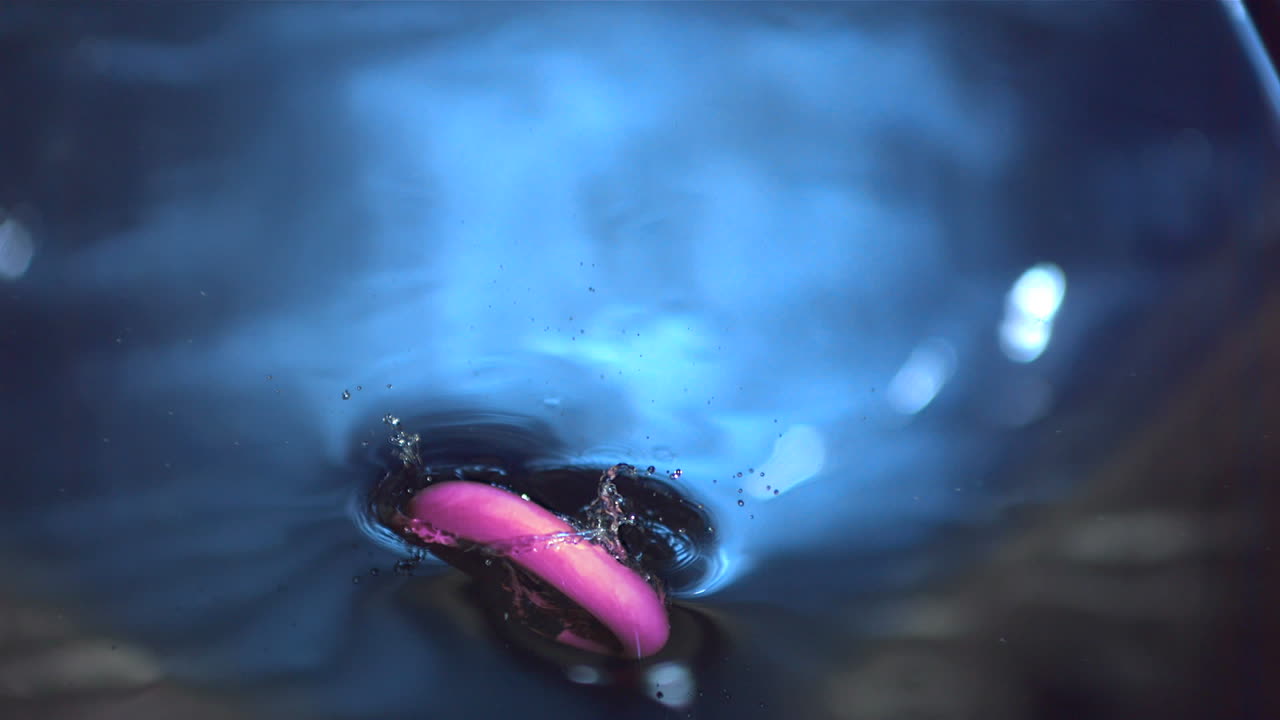 розовое кольцо падает в серую воду.