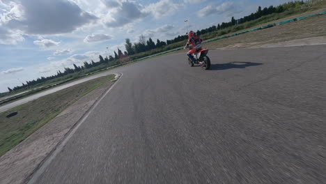 fpv drone pov chasing motorcycle riders speeding around racetrack corners in spain, aerial view