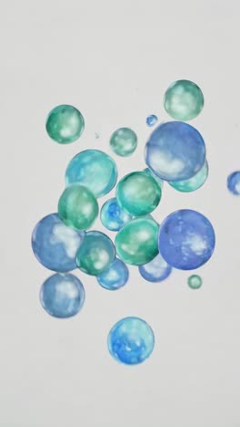 floating blue and green bubbles against a white background, captured from a low-angle view