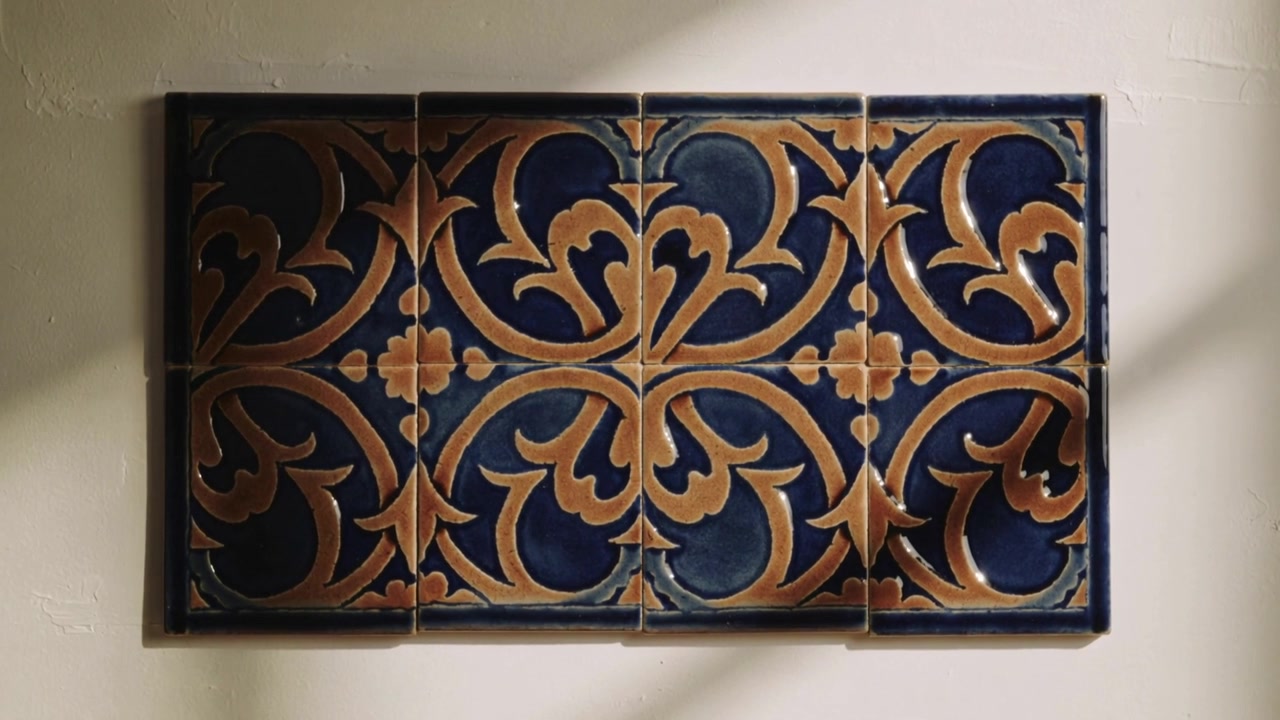 L'operatore avvicina la telecamera, rivelando un pannello di piastrelle montato a parete in casa, che mostra un motivo blu navy e beige.