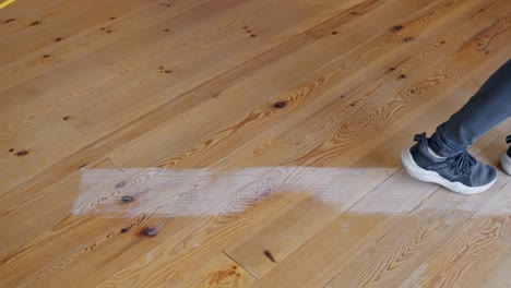 person starts sanding pine wood floors with industrial machine, close up