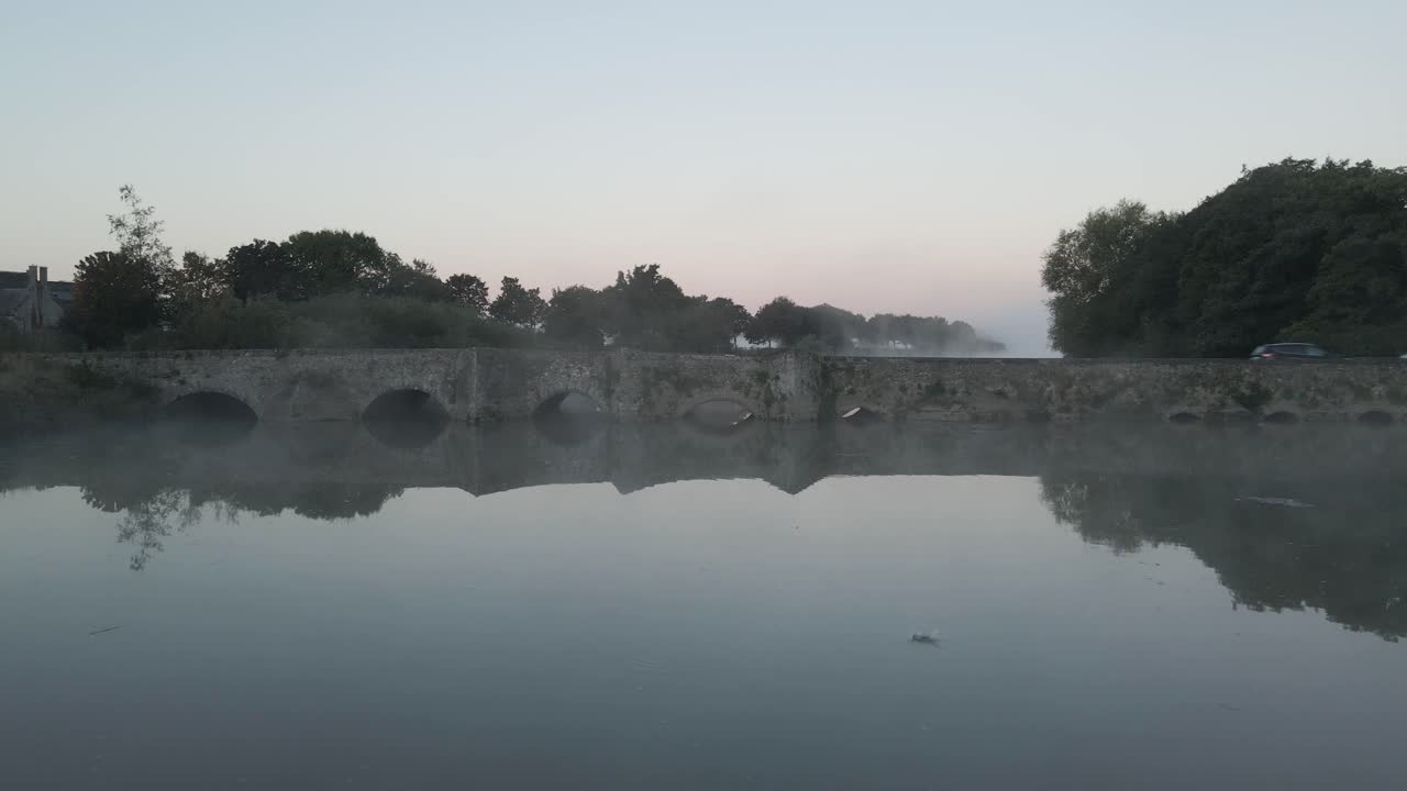 Traffic Over Stone Bridge Near Adare Castle During Foggy Sunrise In County Limerick, Ireland. Aerial Dolly Shot