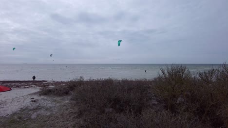 Vista-Total-De-Tres-Kitesurfistas-En-El-Mar-Montando-Las-Olas-Bajo-Condiciones-De-Viento,-Vista-Desde-La-Distancia