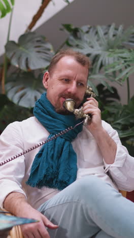 el artista con barba se involucra con un teléfono vintage. el artista establece la paleta para una llamada importante borrando los límites entre las actividades personales y creativas