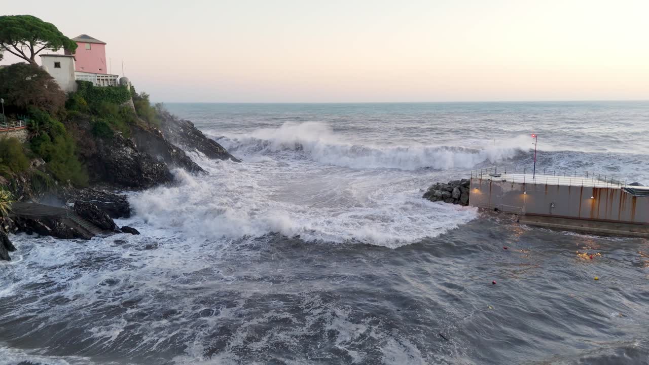 Big foamy sea waves crashing into narrow harbor between cliff and pier