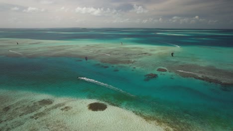 vapor de cayo con kitesurfistas y aguas turquesas, día soleado, vista aérea