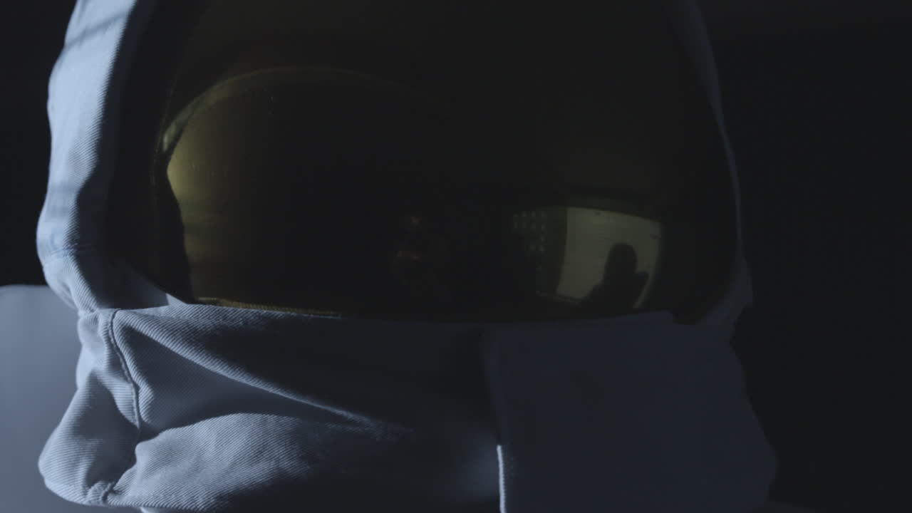 어두운 지역을 둘러보는 금색 헬멧을 쓴 우주비행사