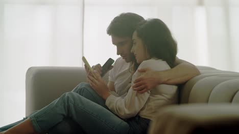 closeup pareja feliz viendo teléfonos móviles en casa. retrato de personas relajadas