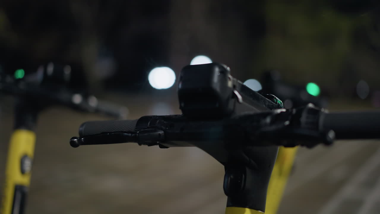 vista en primer plano de una manija de scooter eléctrico estacionado con efectos bokeh suaves a una distancia en el fondo