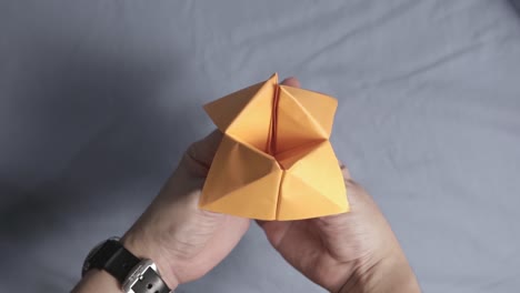 Nahaufnahme-Auf-Händen,-Die-Mit-Orange-Gefaltetem-Papierwahrsager-origami-Spielen