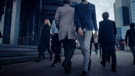 office managers and business people commute to work in the morning or from office on a cloudy day on foot. pedestrians are smart casually dressed. successful people holding smartphones.