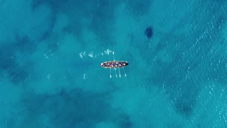 Top-down-aerial-shot-tracking-a-rowing-sports-team-on-beautiful-water,-Spain