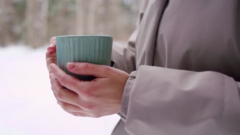 woman holding a mug in a winter forest