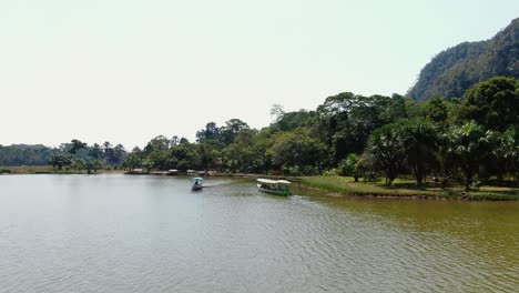 4k-daytime-aerial-video-of-a-boat-coming-in-closer-to-the-camera-on-the-Laguna-de-los-Milagros-in-Tingo-Maria,-the-entry-gate-to-the-Amazon-jungle-in-Peru