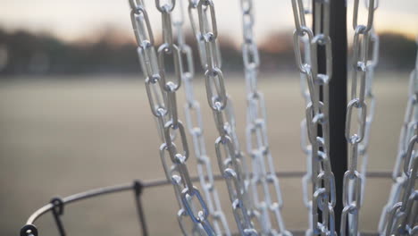 primer plano de las cadenas de la canasta de golf de disco mientras entra un disco de golf de disco