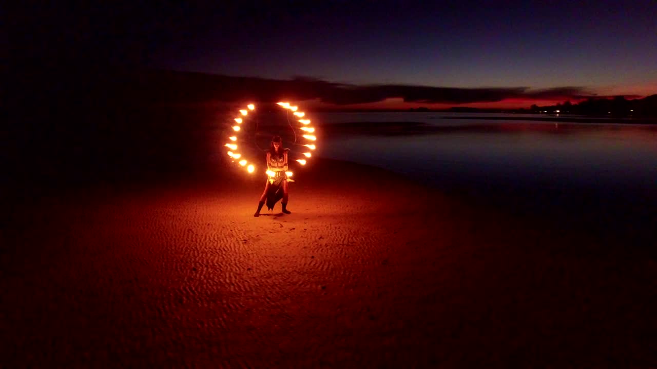 espectáculo de fuego de baile en la playa de bancos de arena al atardecer