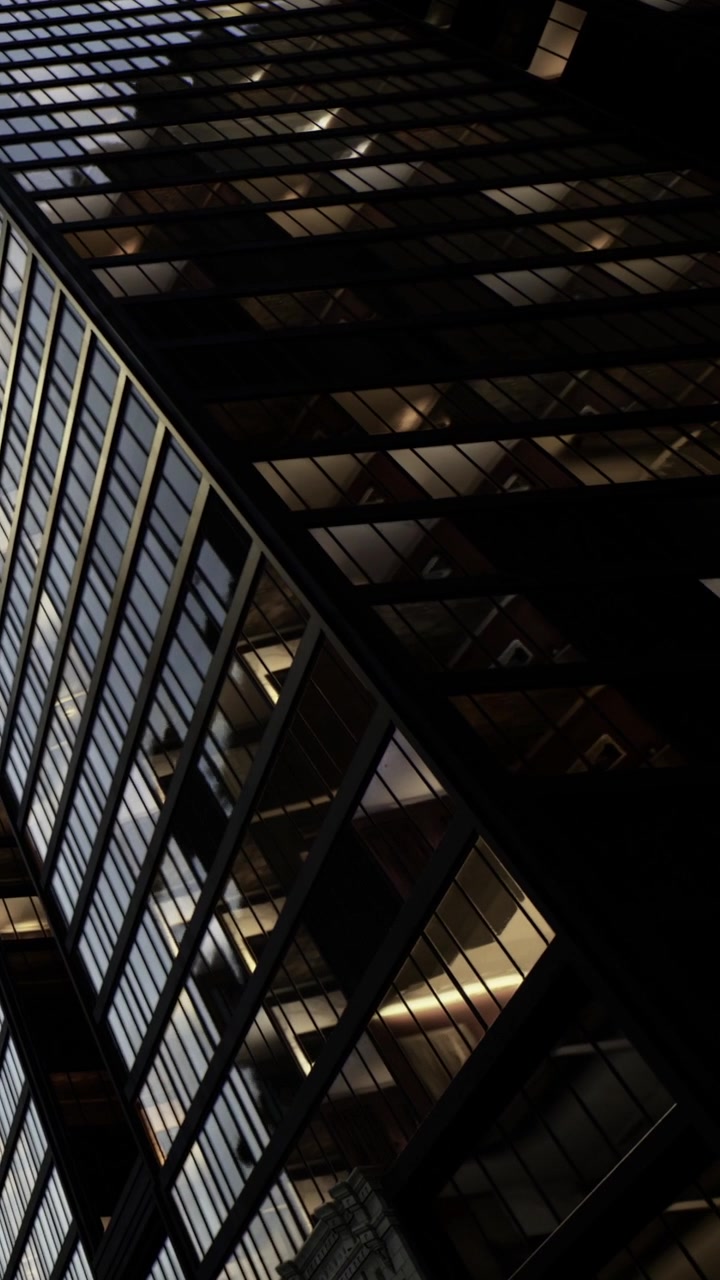 Glass building at night showing lights from different floors