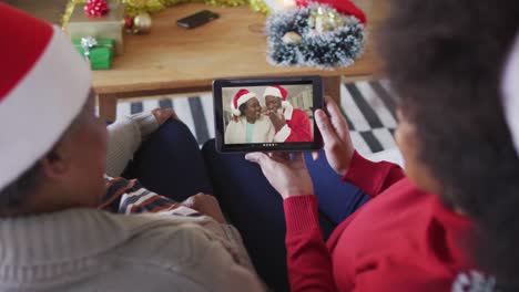 Madre-E-Hija-Afroamericanas-Usando-Una-Tableta-Para-Una-Videollamada-Navideña-Con-Una-Pareja-En-La-Pantalla