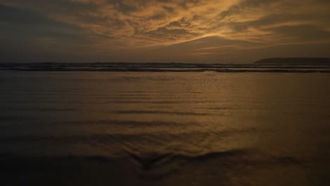 Seascape-view-of-ocean-waves-crashing-on-the-coastline,-at-sunset,-on-a-cloudy-evening