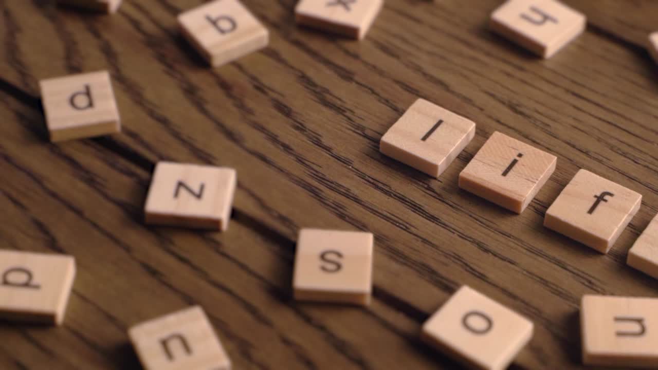 Wooden tiles spell the word life while camera pans across a wooden surface.