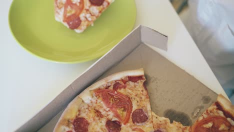 el niño toma una rebanada rota de pizza de la caja de cerca vista superior