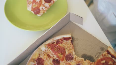 boy takes broken slice of pizza from box close upper view