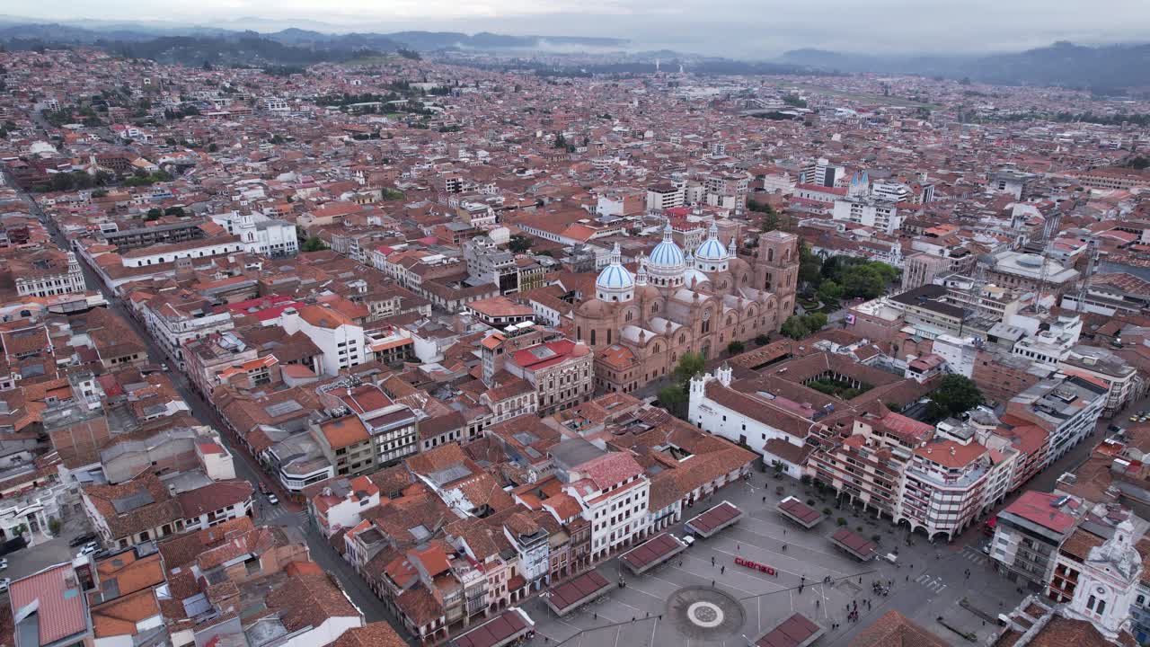 4K 60fps drone shot of Cuenca, Ecuador, featuring the iconic Catedral de la Inmaculada Concepción at the center. A panoramic view of the entire city surrounded by the Andes mountains.