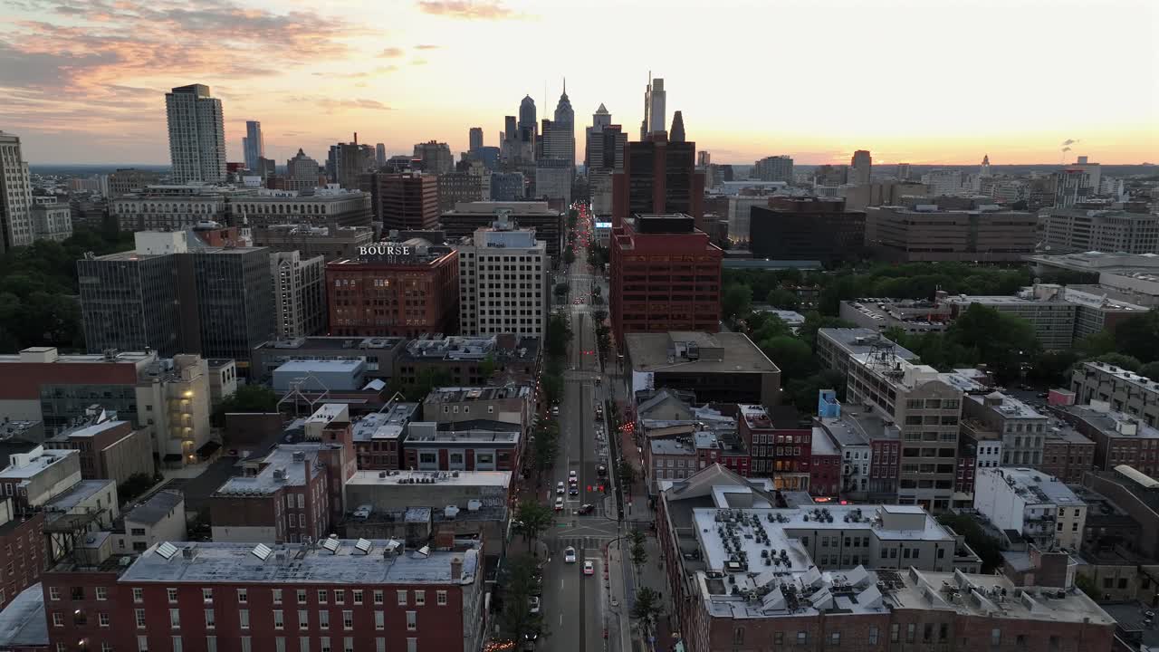 Aerial rising wide shot of Main Street in suburb of Philadelphia. Downtown with skyline in background. Brick houses and homes in metropolis at sunset