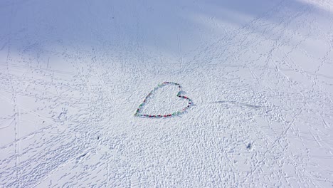 beautiful shot of heart shaped artwork in the snow - frozen colored water laid down on frozen lake - sunny day aerial