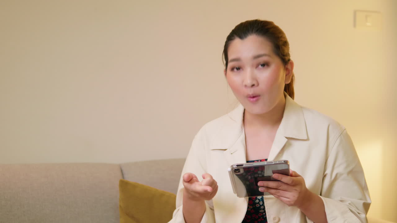 젊은 성인 여성이 평상복을 입고 방에서 말하는 비디오 온라인 커뮤니케이션을 설명하고 인터뷰합니다.