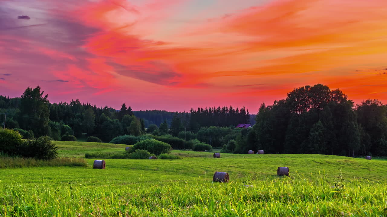 hermosos campos de hierba con fardos de paja que yacen bajo un cielo colorido con cirros en movimiento de día a noche en un lapso de tiempo