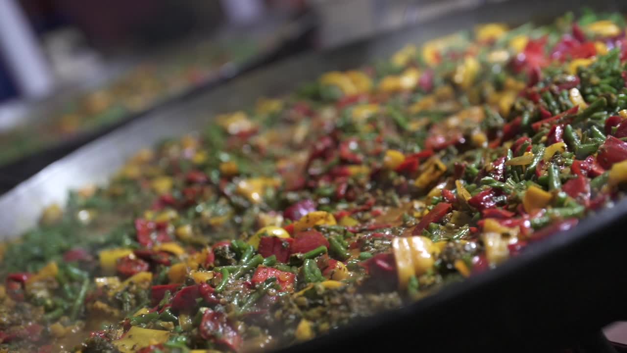 Appetizing detail of colorful peppers, beans, and rice cooking in a large pan, with steam rising from the hot meal