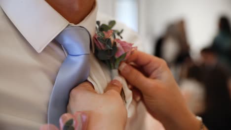 close up shot showing groom getting wedding boutonniere on white shirt during marriage