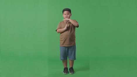 cuerpo lleno de hombre asiático haciendo un gesto de tiempo con las manos mientras está de pie en el fondo de la pantalla verde