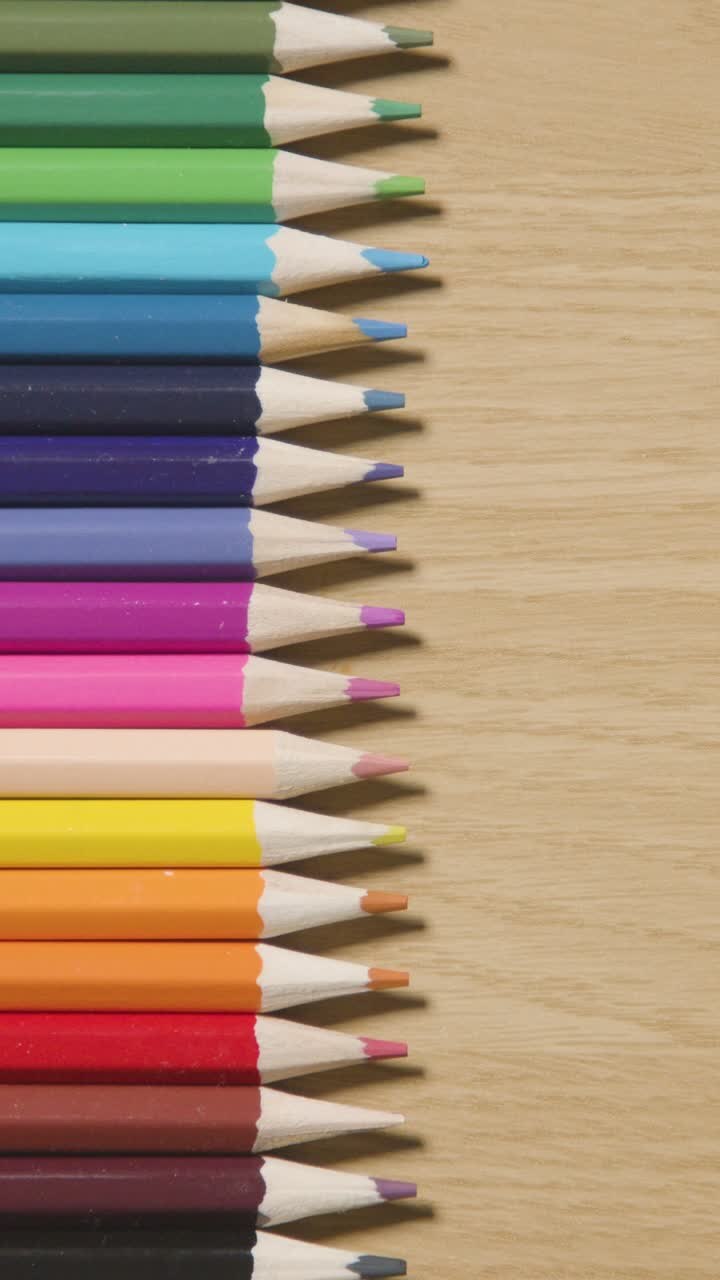 Vertical Video Of Coloured Pencils Arranged In A Line On Wooden Background
