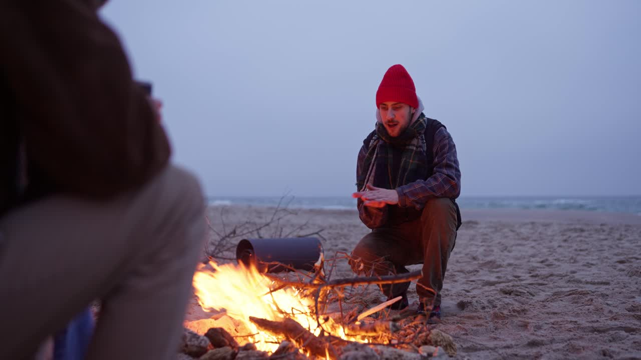 Friends by the campfire on the beach at night