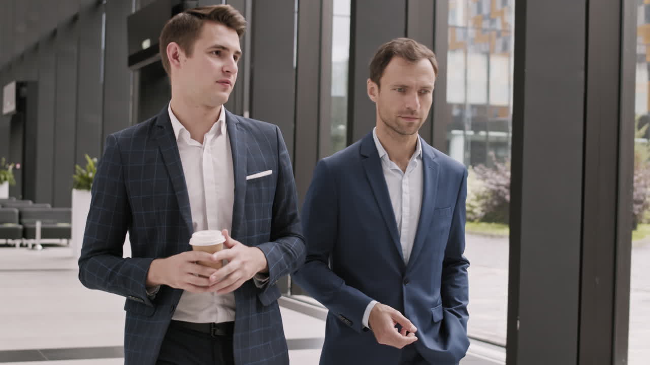dos hombres de negocios yendo a lo largo de la sala de la oficina y charlando