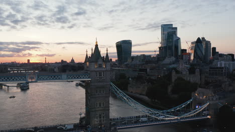 Forwards-fly-above-Thames-River-towards-one-of-pillars-of-Tower-Bridge.-Colourful-sunset-sky.-London,-UK