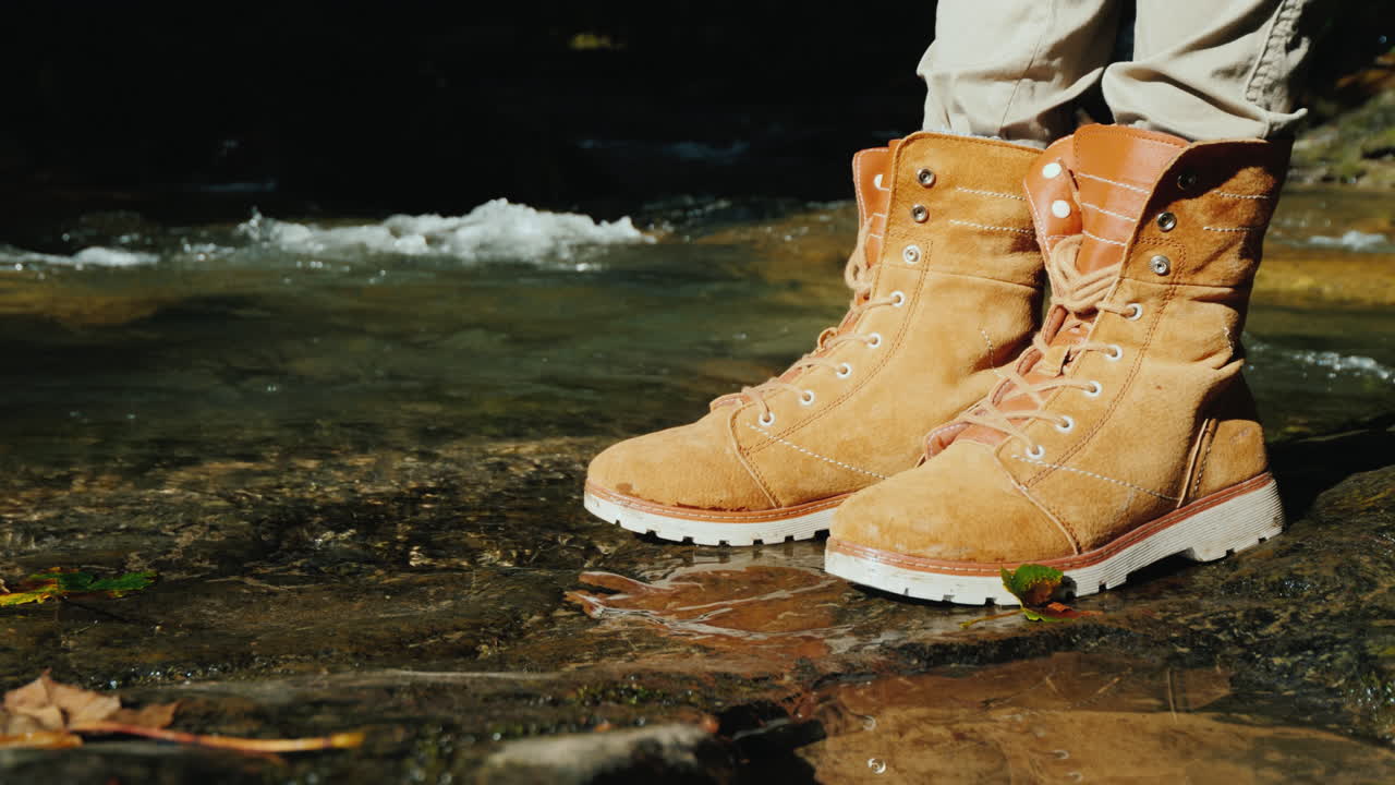 un turista con botas de trekking se encuentra cerca de un arroyo de montaña, caminatas y descanso activo