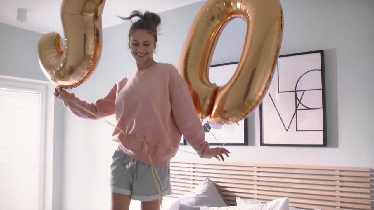 Donna con palloncini dorati che festeggia il suo compleanno a letto