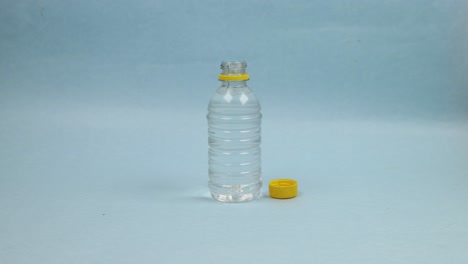 파란색 배경에 있는 병의 맑은 물 음료 - 정지 동작